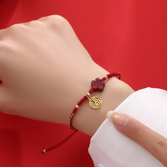Red string bracelet with gold Fu character pendant and cinnabar flower bead worn on wrist, adjustable Chinese lucky cord jewelry for women