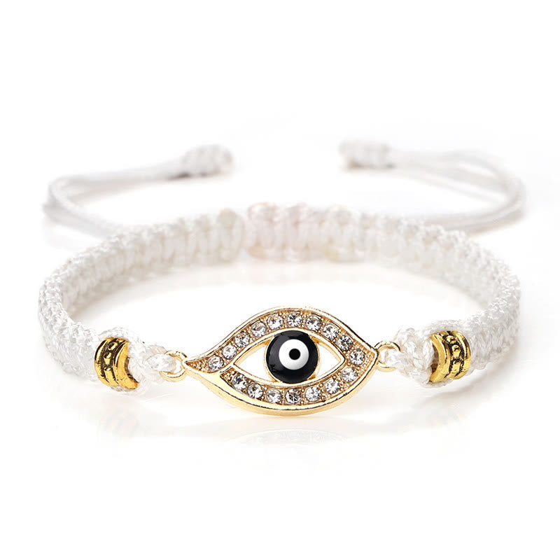 White cord evil eye bracelet with gold pave crystal charm on white background