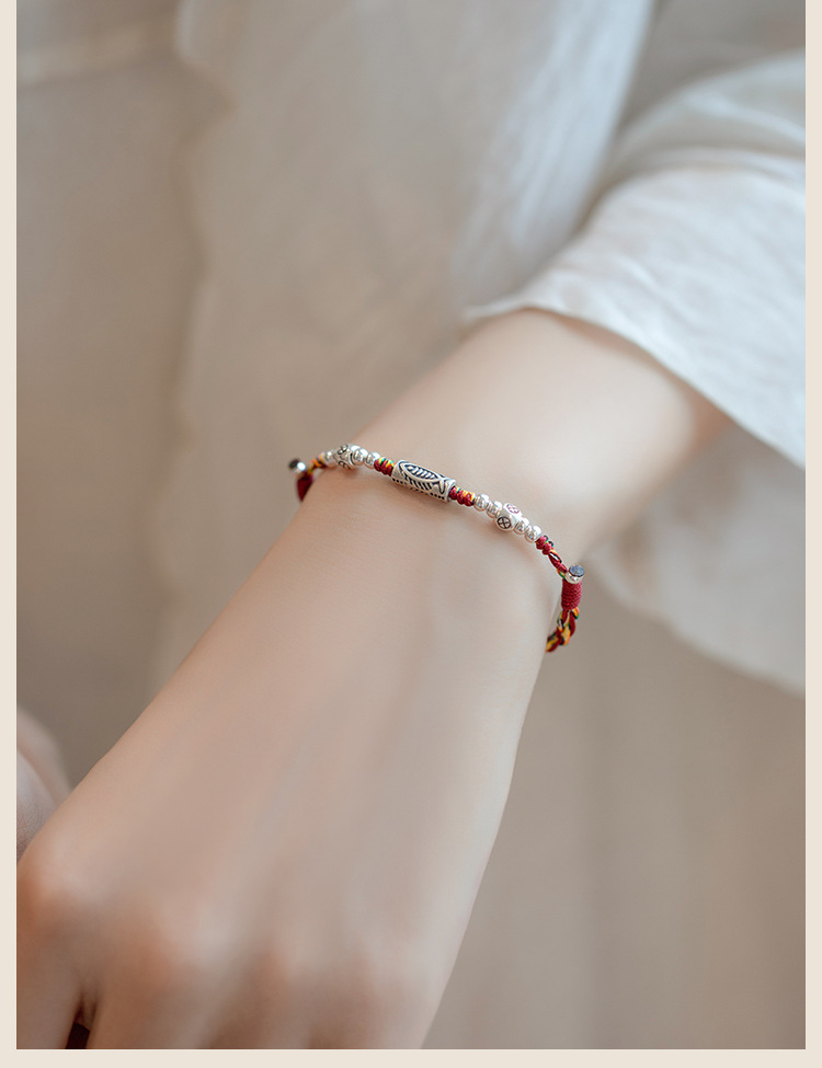 Koi Red String Bracelet – multicolor braided band worn on wrist with white sleeve, everyday luck jewelry