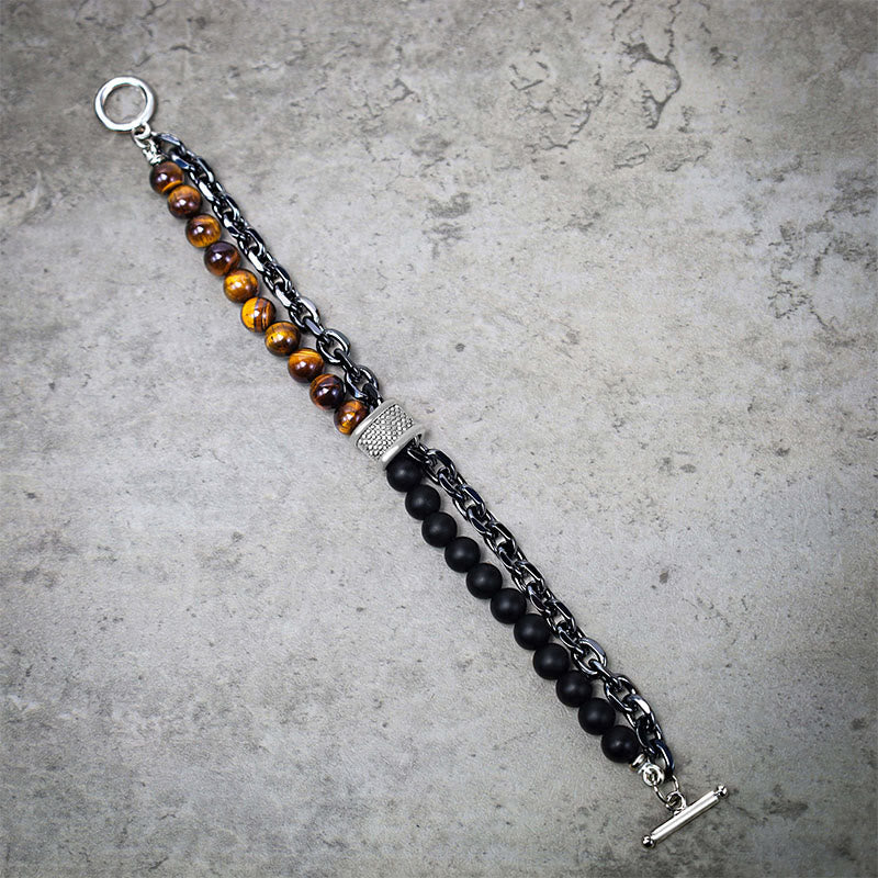 Tiger Eye Lazurite Malachite Protection Bracelet – Diagonal full-length view showing tiger's eye, black onyx beads, rolo chain, pave-set barrel accent, and toggle closure on gray concrete