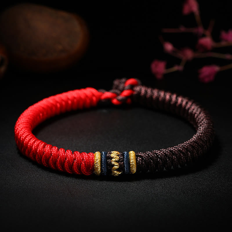 Two-tone Tibetan five-color king kong knot bracelet featuring red and burgundy cord sections with gold navy and cream ornamental knot centerpiece