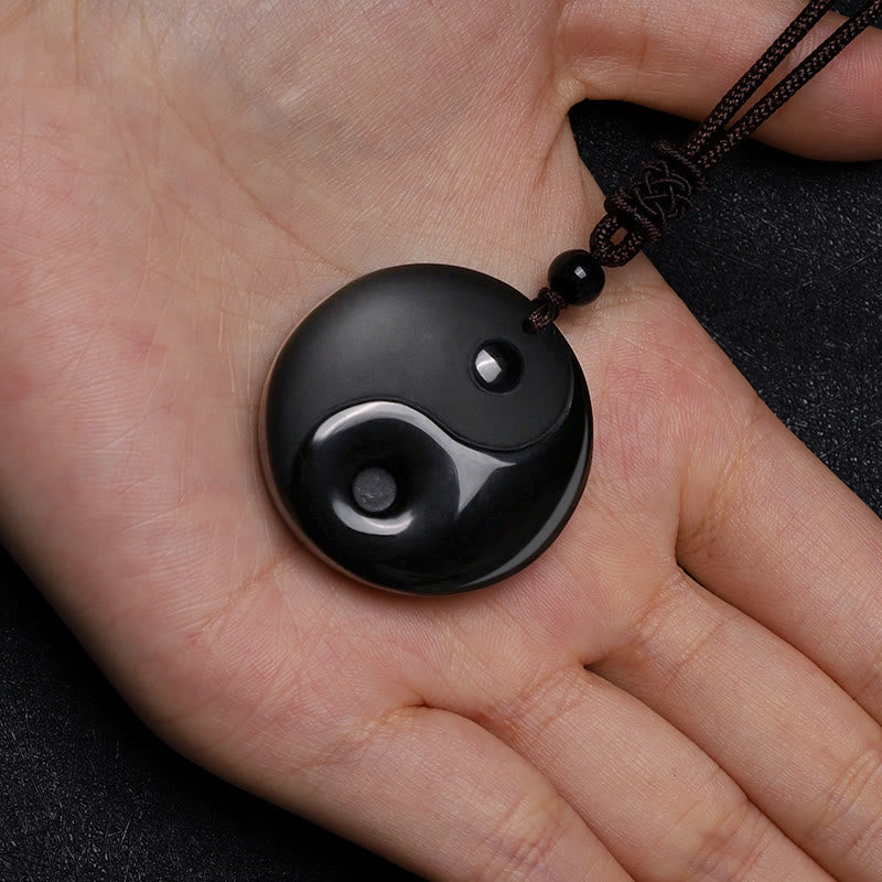 Black Obsidian Nine-Character Mantra Necklace – Obsidian Yin-Yang pendant held in hand, scale reference, spiritual jewelry