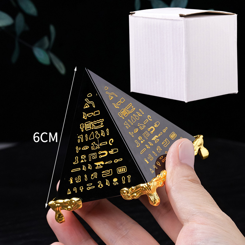 Hand holding 6cm black obsidian Egyptian scripture pyramid with gold engravings and feet, white gift box, size reference, energy protection decor