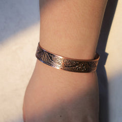 Tree of life copper magnetic bracelet worn on wrist showing detailed Celtic knotwork and nature engraving in warm natural lighting