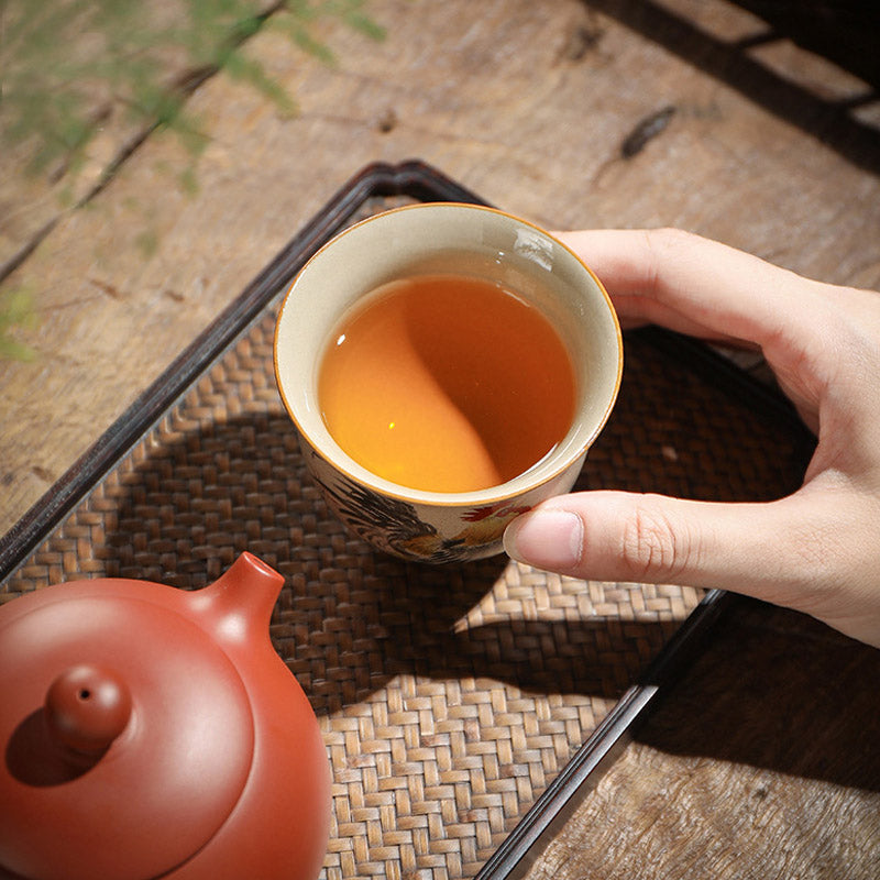 Chinese Zodiac Ceramic Teacup - holding painted bird cup with amber tea, rattan tray setting