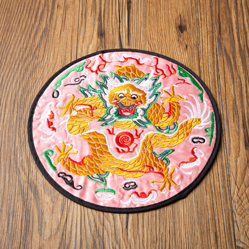 Dragon Embroidery Tea Cup Coaster Mat - pink satin base with front-facing dragon, overhead on wood grain, vibrant
