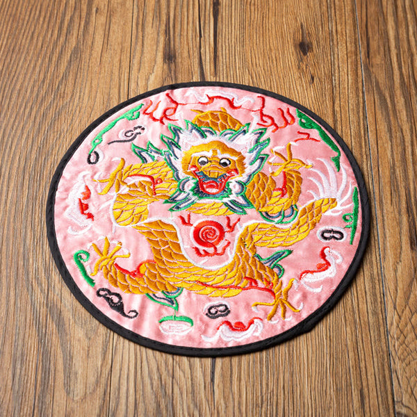 Dragon Embroidery Tea Cup Coaster Mat - pink satin base with front-facing dragon, overhead on wood grain, vibrant