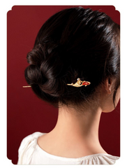 Koi Hairpin – worn in a dark updo from back view, burgundy backdrop, white blouse, luck charm