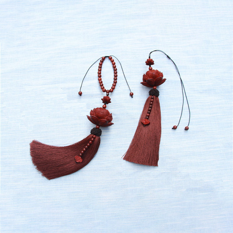 Red Sandalwood Lotus Tassel - overhead view on textured fabric, curved tassel flow