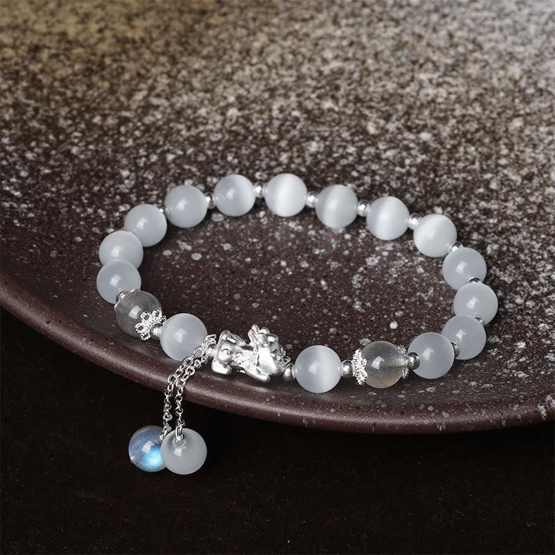 Cat's Eye PiXiu Bracelet – Bracelet on dark ceramic plate with silver PiXiu and dangling charms