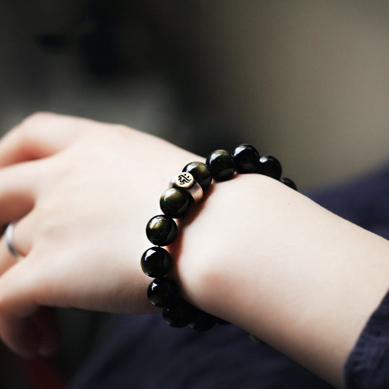 Zodiac Natal Buddha Obsidian Silver Bracelet - On wrist with silver Buddha bead, warm bokeh background