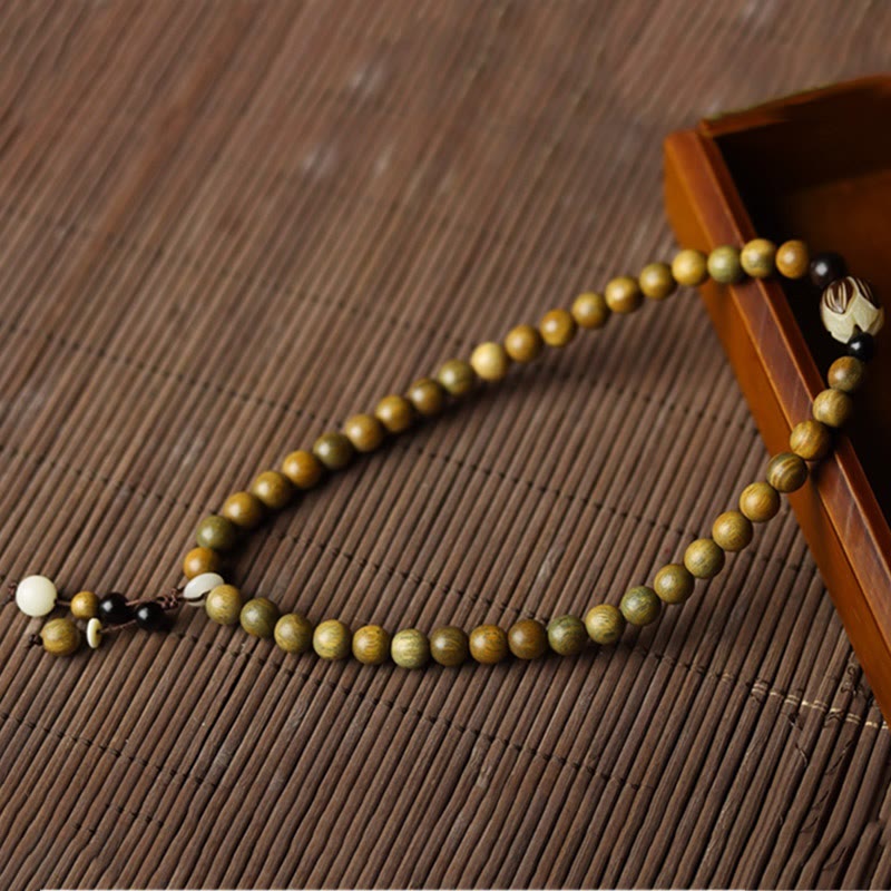 Green Sandalwood Lotus Bracelet – draped over wooden box on bamboo mat, artisan staging