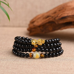 Zodiac Obsidian PiXiu Mala – Side view black bead wraps with gold PiXiu on linen