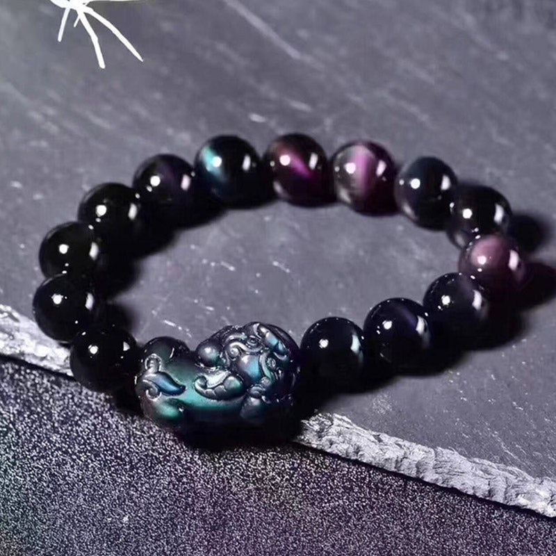 Feng Shui Rainbow Obsidian Bracelet – black beads purple green sheen Pixiu flat lay, crystal bracelet