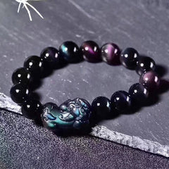 Feng Shui Rainbow Obsidian Bracelet – black beads purple green sheen Pixiu flat lay, crystal bracelet