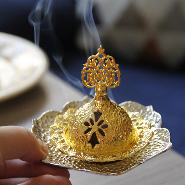Gold Leaf Coaster Incense Burner with active smoke, held by hand on blue background, alloy incense holder