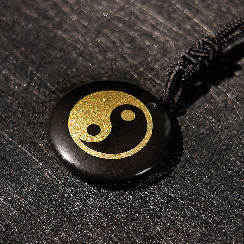 Yin Yang Crystal Necklace – Black obsidian disc pendant with gold glitter yin-yang inlay, polished glossy stone on black brai