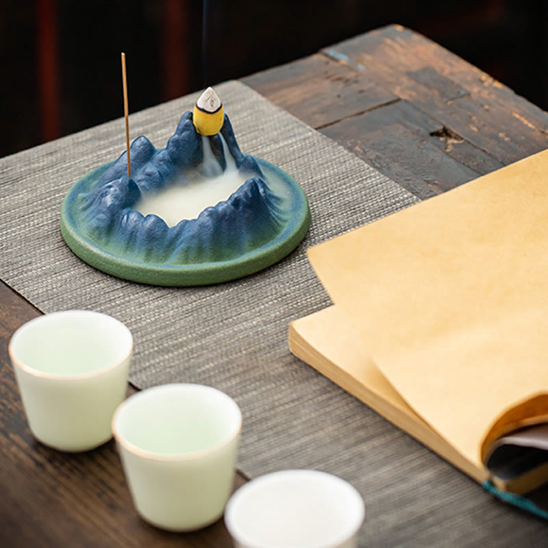Ceramic Backflow Incense Burner – Mountain dish with smoke waterfall, tea cups and book on rustic wood, zen