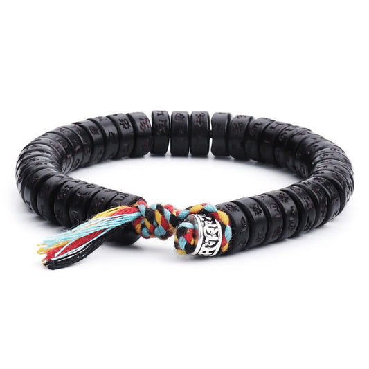 Coconut Shell Mantra Bracelet - Full view of black engraved beads with colorful tassel on white, Tibetan mala