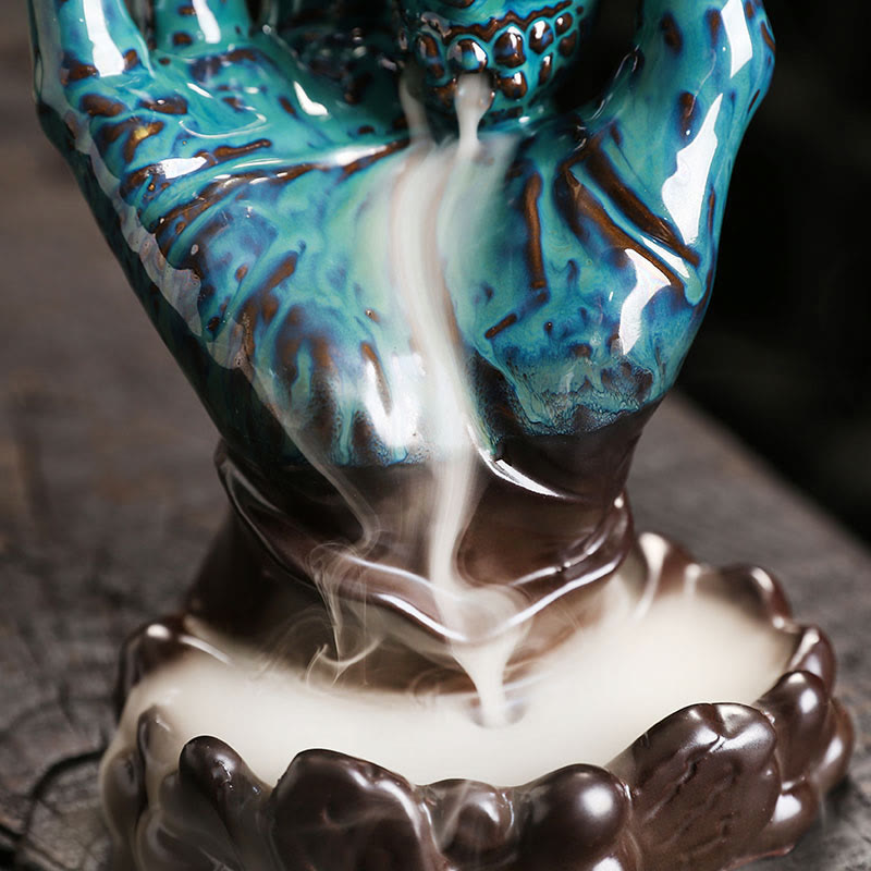 Ceramic Ghost Hand Skull Incense Burner – Low-angle shot of skull in cupped hands, smoke waterfall, copper-brown glaze