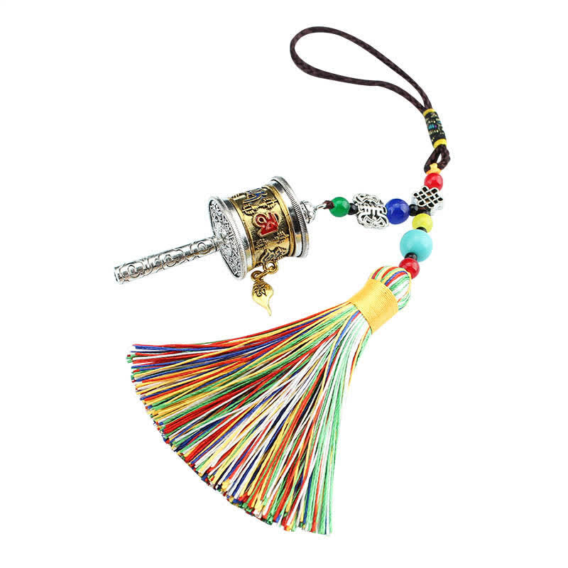 Tibetan Prayer Wheel Tassel – Silver gold prayer wheel with blue gemstone and beads on wood backdrop
