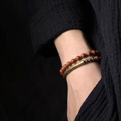 Stacked couple bracelets worn on wrist - red jasper beaded bracelet with antique bronze cuff bangle, earthy terracotta and aged gold tones lifestyle photography