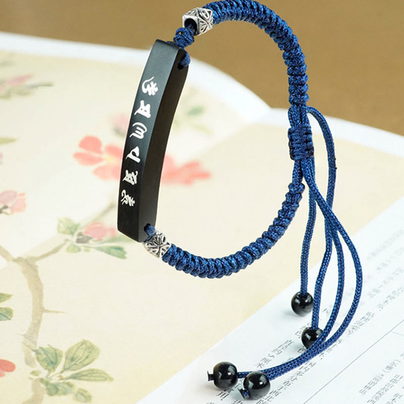 Om Mani Padme Hum Cord Bracelet – Resting on floral artwork page, silver bead accents visible