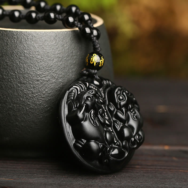 Double PiXiu Necklace – Black obsidian PiXiu disc leaning on ceramic cup side angle, feng shui necklace
