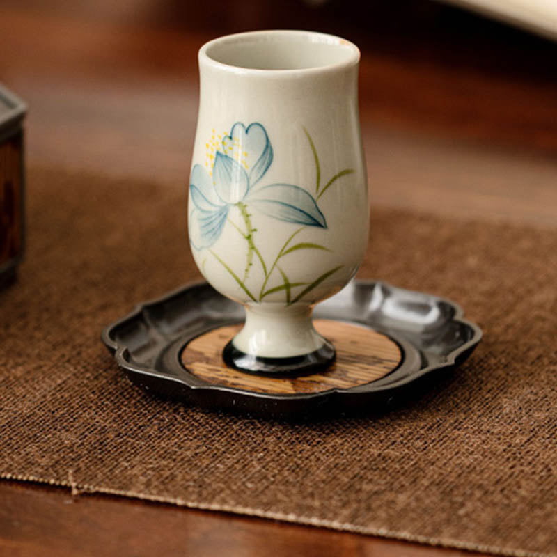 Hand Painted Lotus Tea Cup – tall stemmed cup held in hand, blue lotus with crackle glaze, warm bokeh, mindful