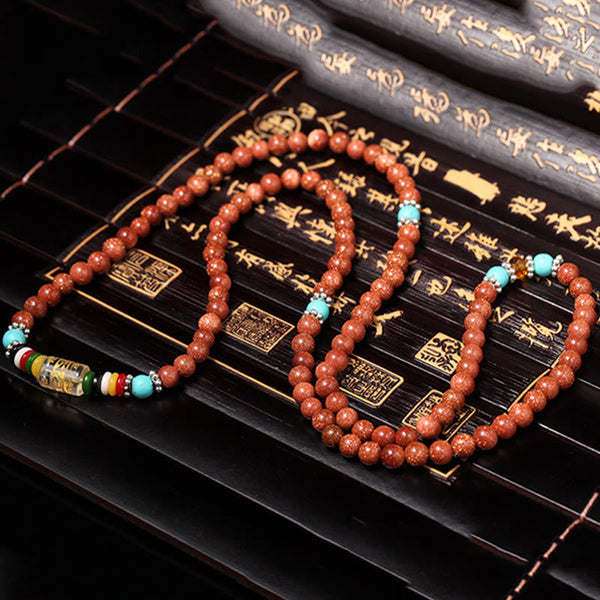 Goldstone Mala Bracelet – full 108-bead mala necklace draped on bamboo mat with seal stamps