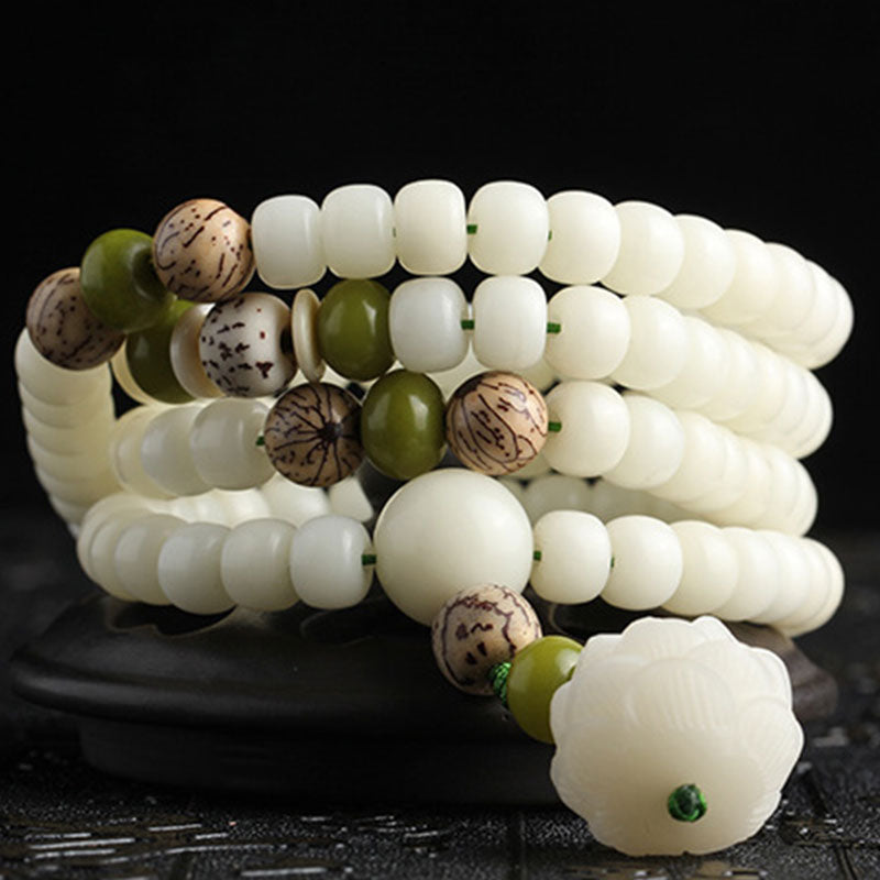 Bodhi Seed Lotus Mala - elegant S-curve coil on dark surface, lotus pendant focal point, studio shot