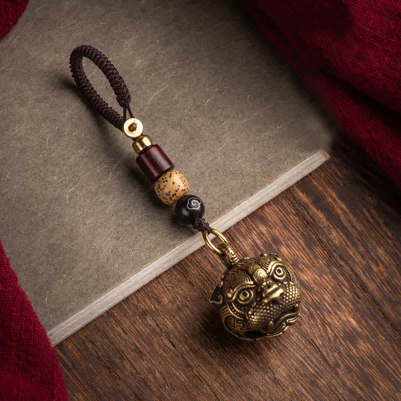 Pixiu Wealth Copper Key Chain – on antique book and wood side angle with red fabric accent, brass pixiu keychain