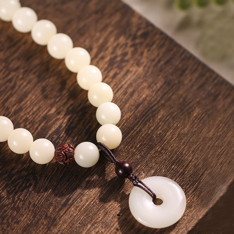 Bodhi Seed Sandalwood Lotus Bracelet - diagonal layout on wood grain, peace buckle dangle with carved bead