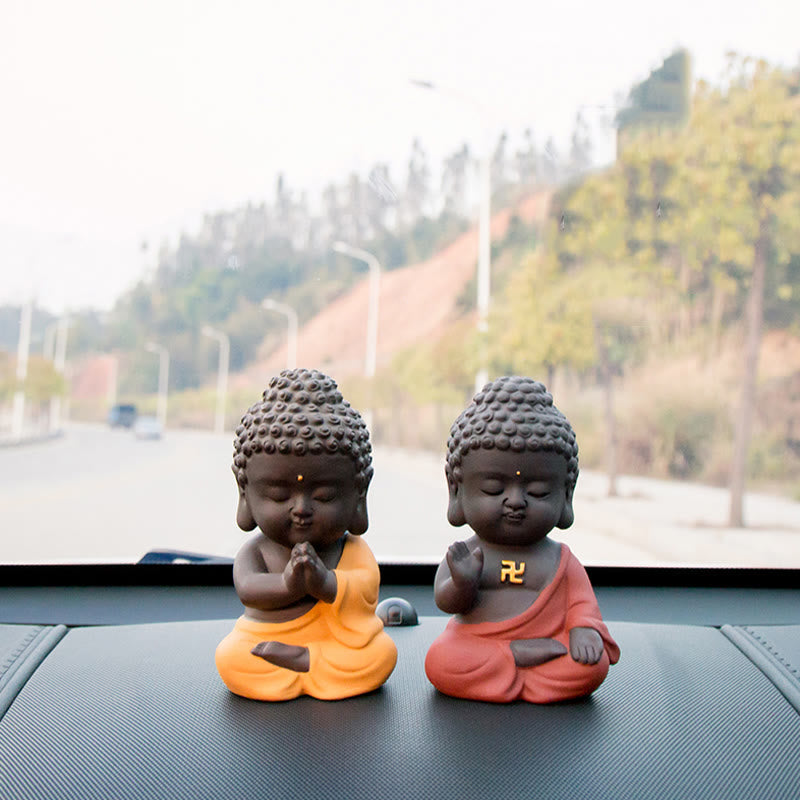 Small Buddha Purple Clay Decoration – two robe-color variants side by side on dashboard, prayer vs blessing gestures, complem