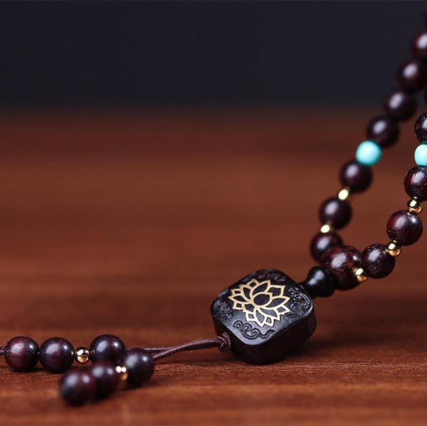 108 bead red sandalwood mala bracelet draped over Yixing clay teapot with Heart Sutra inscription, turquoise accents and gold lotus guru bead on dark wood surface