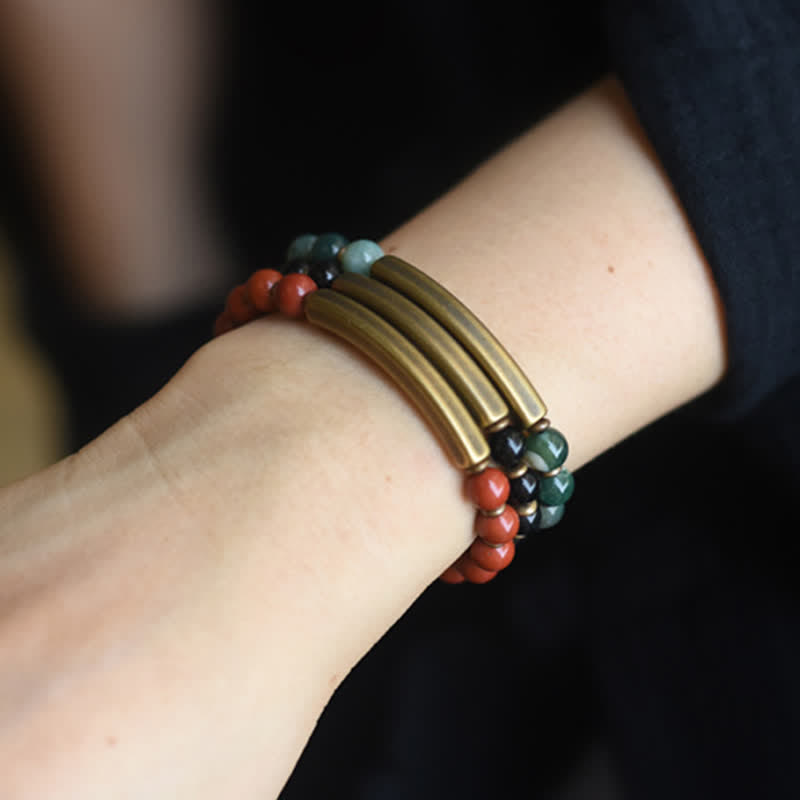 Triple-strand bracelet on wrist showing three antique brass parallel bars with red jasper, moss agate and black obsidian bead strands, couples matching jewelry