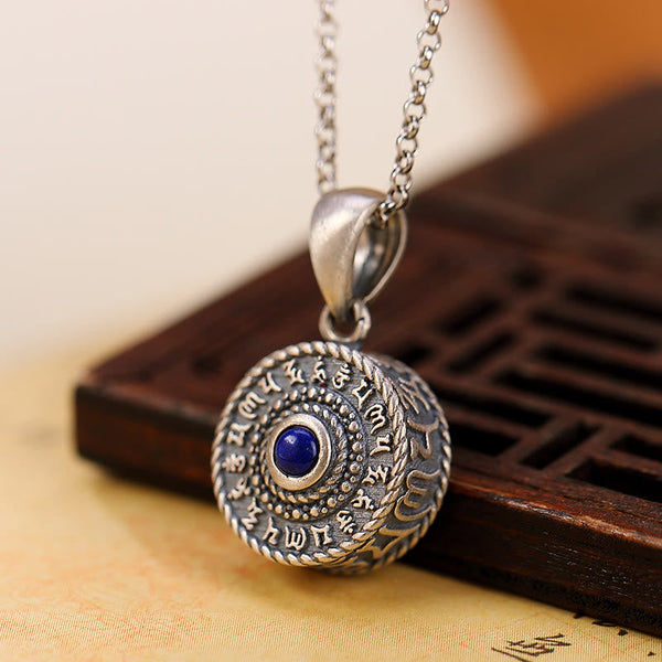 Om Mani Padme Hum Pendant – Angled shot on carved wooden tray with blue center stone, spiritual necklace