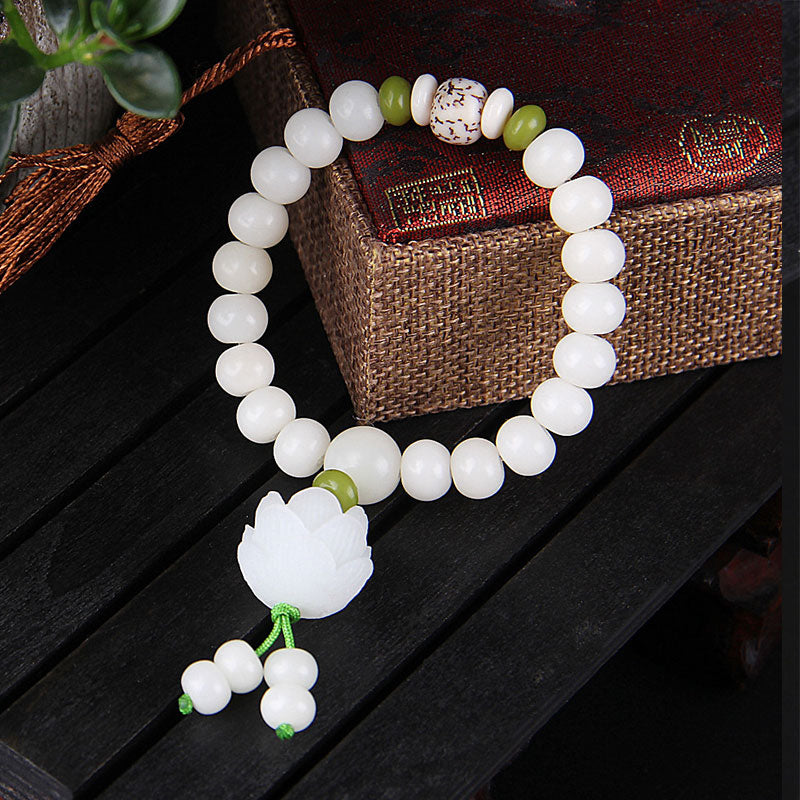White Bodhi Seed Luck Bracelet – Lotus pendant with tassel dangles on carved wooden display, spiritual gift