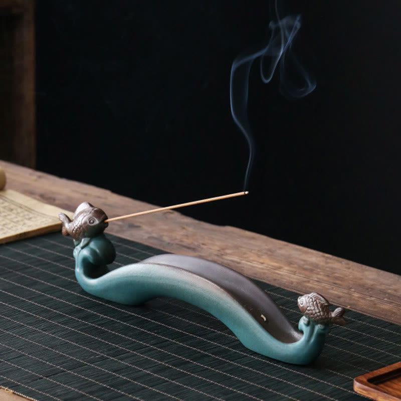 Double Koi Fish Mountain Incense Burner - teal ceramic holder with bronze koi on dark bamboo mat, smoke trail