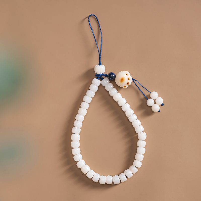 White Jade Bodhi & Jadeite Crystal Phone Charm – White barrel bodhi beads with lucky cat charm and blue cord on warm beige background