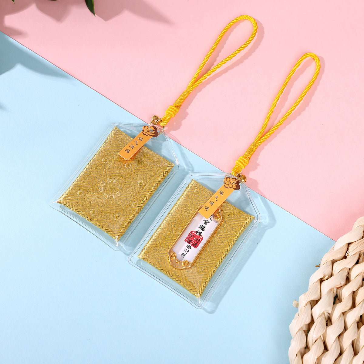 Two yellow wealth blessing amulets on pink and blue background
