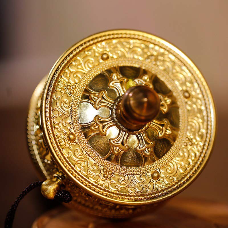 Sandalwood Tibetan Prayer Wheel – Top-down view of brass prayer wheel on carved wood stand, filigree patterns, warm studio...