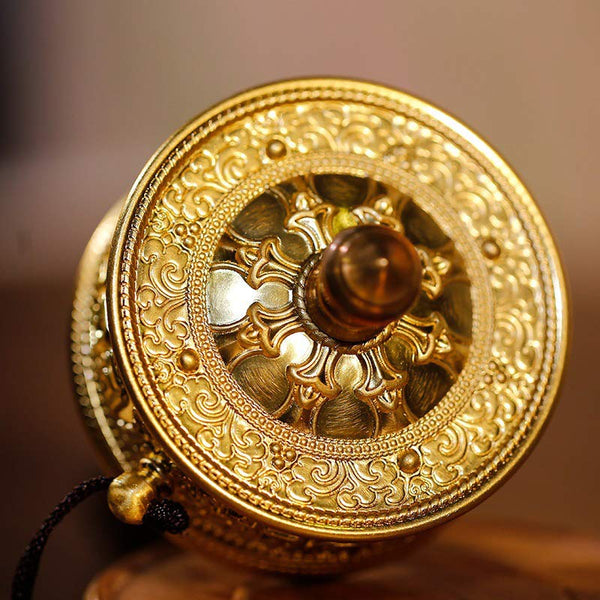 Sandalwood Tibetan Prayer Wheel – Top-down view of brass prayer wheel on carved wood stand, filigree patterns, warm studio...