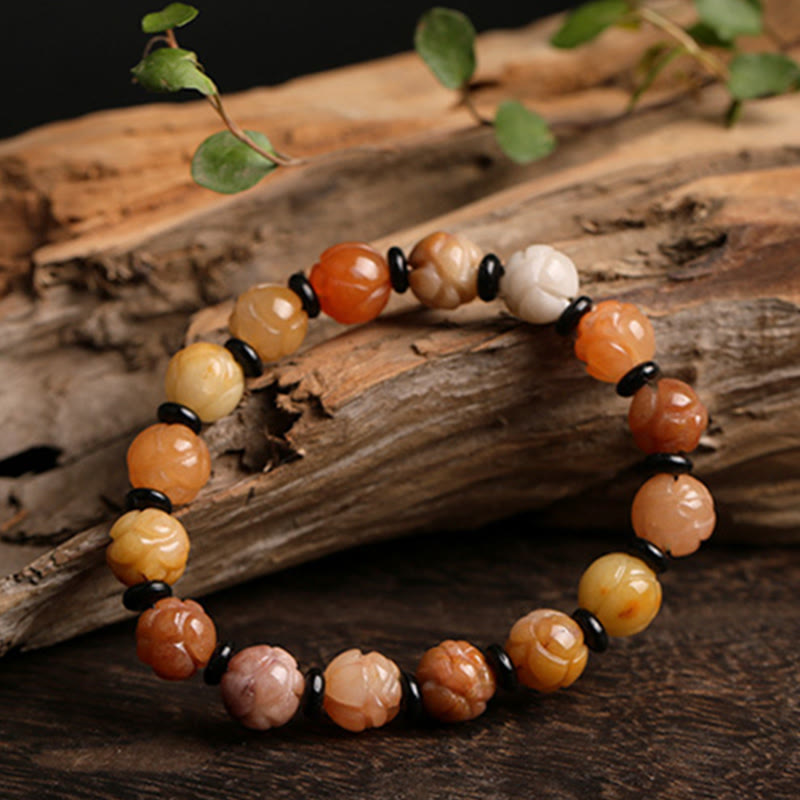 Golden Silk Jade Lotus Bracelet – Carved lotus beads on driftwood with green foliage, warm earth tones, lotus jade