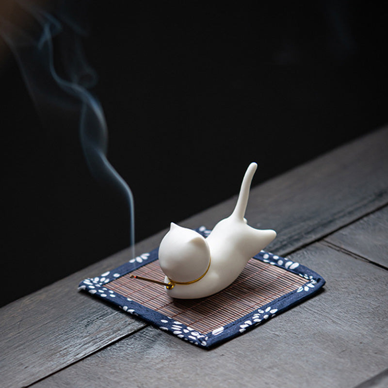 White ceramic cat incense burner in yoga stretch pose, gold collar, smoke trail
