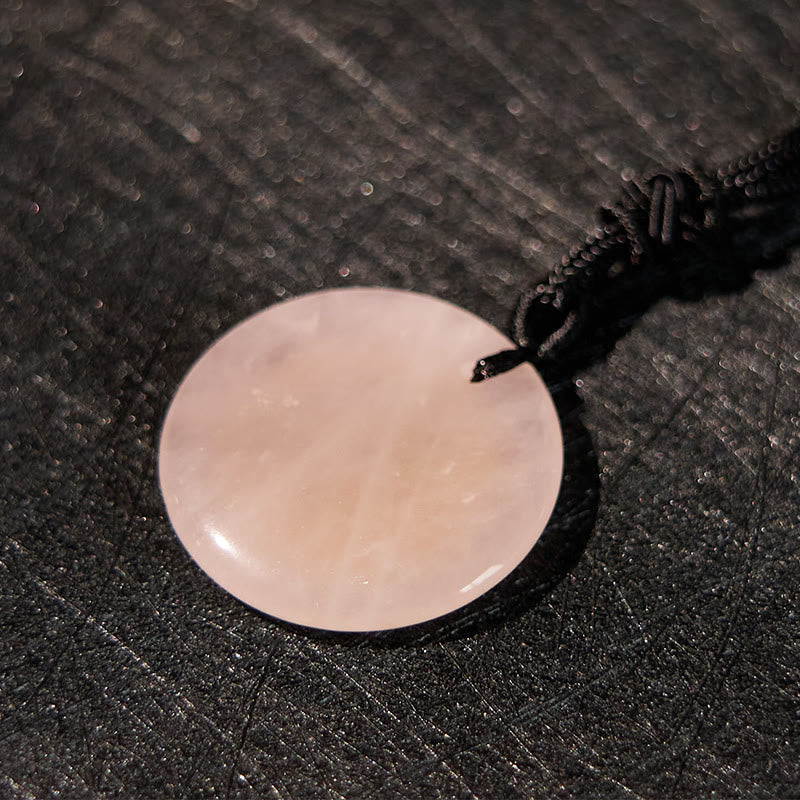 Yin Yang Crystal Necklace – Round pink rose quartz disc pendant with smooth polished finish, pale translucent stone on dark b