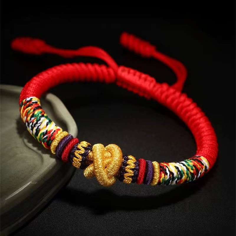 Tibetan Mantra Bracelet – Gold prosperity knot with multicolor braided cord on ceramic dish, lucky bracelet