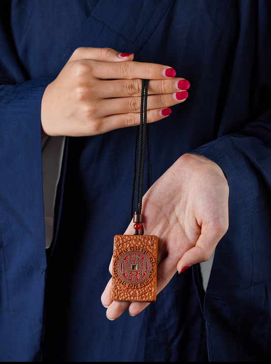 Shan Gui Wood Pendant – hands holding pendant on blue robe, Daoist protection amulet