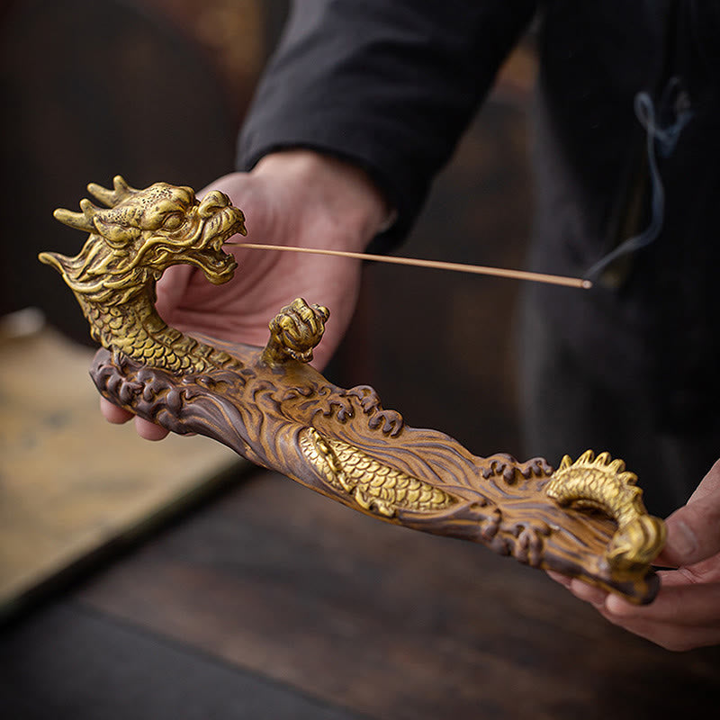Dragon Protection Incense Burner – hand adjusting incense stick on dark textile, peanuts nearby, ritual moment
