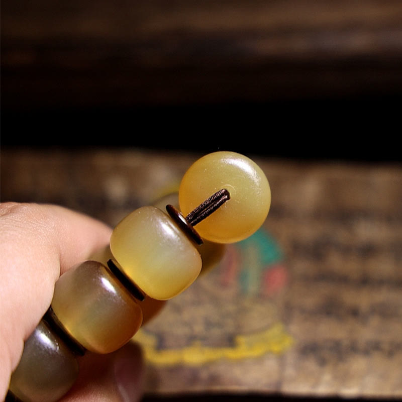 Tibetan Sheep Horn Skull Bracelet – Loose amber beads arranged on thangka background, material showcase